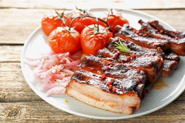Lezzetli domuz pirzolası, kurutulmuş domates ve ahşap masada soğan, yakın plan.