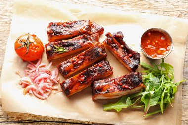 Lezzetli domuz pirzolası, sos, roka ve soğan ahşap masa, üst manzara.