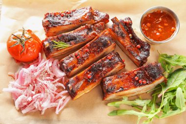 Lezzetli domuz pirzolası, sos, roka ve parşömen kağıdının üstünde soğan.