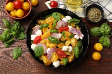 Sarı domatesli lezzetli salata, fesleğen, soğan ve ahşap masada mozzarella peyniri.