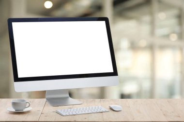 Boş ekranlı bilgisayar monitörü ve bulanık arka planda tahta masanın üzerinde fincan. Tasarım için model
