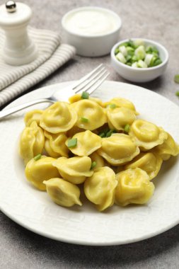 Gri desenli masada yeşil soğan ve çatallı lezzetli hamur tatlısı, yakın plan.