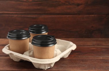 Tahta masadaki karton tutacakta kağıt kahve fincanları. Metin için boşluk