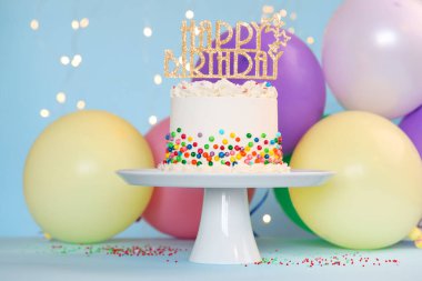 Renkli süslemeli nefis bento keki ve bulanık ışıklara karşı açık mavi masada mutlu yıllar.