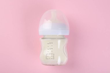 Pembe arka planda sütle beslenme şişesi, üst görünüm