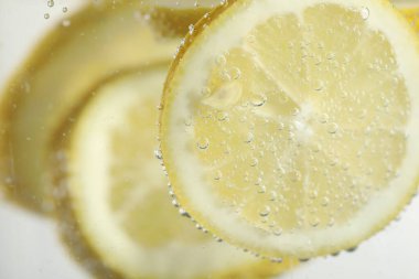 Arka planda limon dilimleri olan soda, yakın plan.