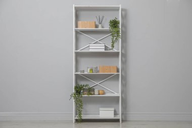 Different items on shelving unit near light grey wall