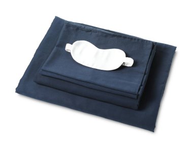 Beyaz arka planda ipeksi çarşaf ve uyku maskesi yığını