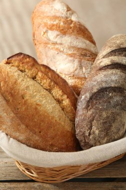 Tahta masadaki sepetin içinde farklı somunlar, yakın çekim.