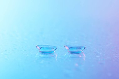 Kontakt lensler ve su damlaları mavi ayna yüzeyine, yakın plan.