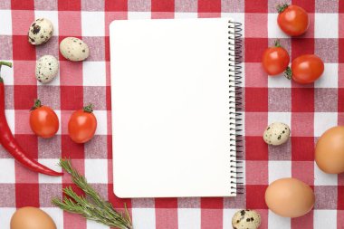 Boş tarif kitabı ve kareli masa örtüsü üzerindeki ürünler, düz konum