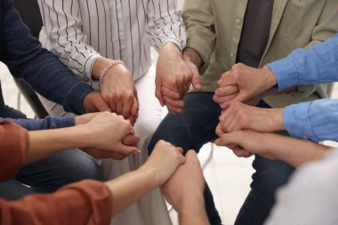 Grup psikoterapi seansı sırasında el ele tutuşan insanlar kapalı mekanda, yakın çekim