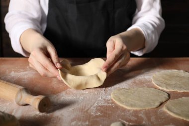 Khinkali yapıyorum. Mutfaktaki masada hamur şekillendiren kadın, yakın plan.