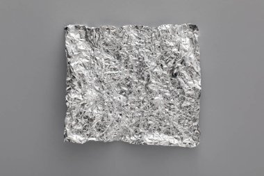 Açık gri arkaplanda buruşuk alüminyum folyo parçası, üst görünüm