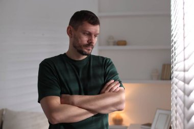 Depresyondaki adam pencereden dışarı bakıyor.