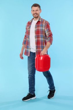 Açık mavi arka planda plastik kutu tutan adam.