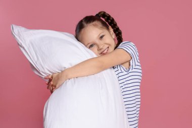 Pembe arka planda yastığı olan tatlı bir kız.