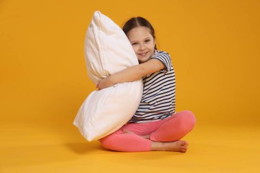 Turuncu arka planda yastığı olan tatlı bir kız.