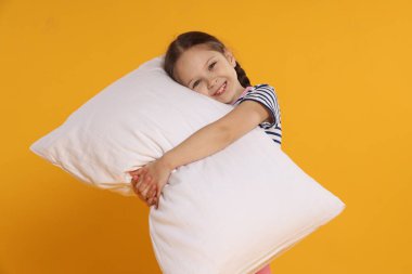 Turuncu arka planda yastığı olan tatlı bir kız.