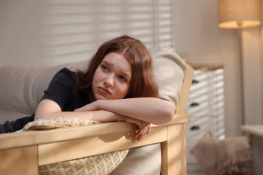 Evdeki kanepede oturan üzgün genç kız.