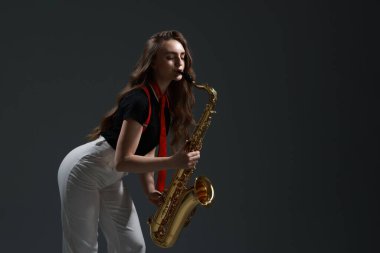 Gri arka planda saksafon çalan profesyonel bir müzisyen. Metin için boşluk