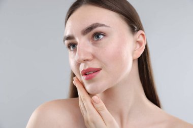 Gri arka planda sağlıklı ciltli bir kadın.