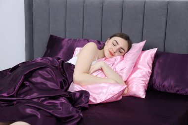 Kadın yatakta ipek çarşaflarla uyuyor.
