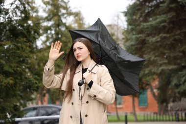 Şemsiyesi kırık bir kadın dışarıda rüzgarla savaşıyor.