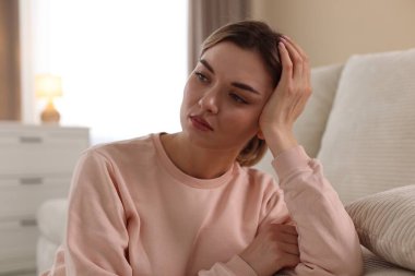 Evdeki kanepenin yanındaki depresif genç kadın.