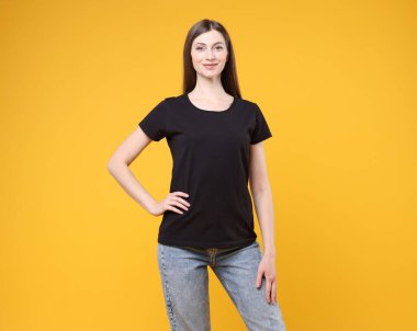Turuncu arka planda siyah tişört giyen bir kadın. Tasarım için model