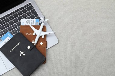 Pasaportlar, uçuş biletleri, uçak modeli ve koltukta dizüstü bilgisayar, üst manzara. Metin için boşluk