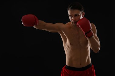 Siyah arka planda dövüşen boks eldivenli adam.