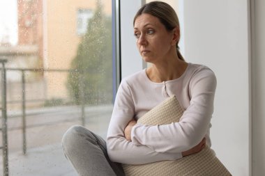 Depresyondaki kadın pencereden dışarı bakıyor, mesaj için boşluk var.
