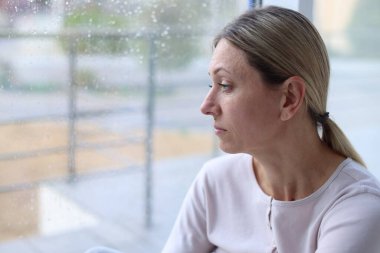 Depresyondaki kadın pencereden dışarı bakıyor, mesaj için boşluk var.