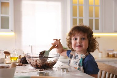 Yemek tarifi. Küçük çocuk mutfaktaki masada kurabiye için para kazanıyor. Metin için boşluk