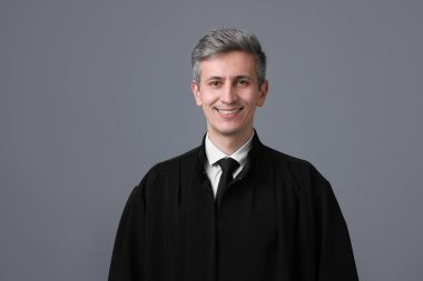 Gri arkaplanda mahkeme elbisesi içindeki gülümseyen yargıç portresi