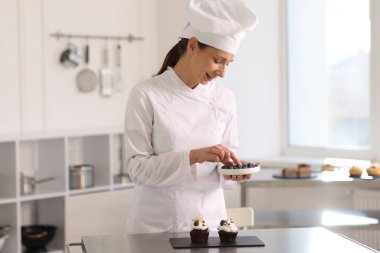 Böğürtlenli şekerlemeci mutfakta kek süslüyor.