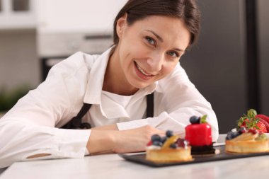 Masada lezzetli tatlıları olan mutlu bir pastacı.