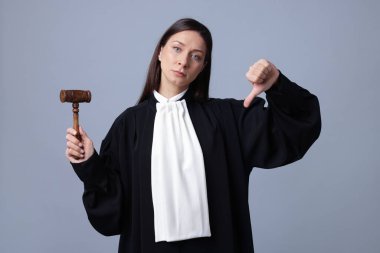 Gri arkaplanda baş parmak gösteren çekiçli yargıç