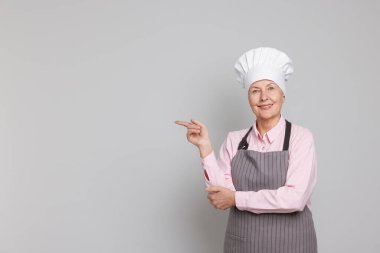 Açık gri arka plandaki bir şeyi işaret eden profesyonel bir şekerci. Metin için boşluk