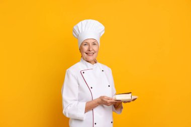 Turuncu arka planda kek dilimi olan profesyonel pasta şefi.