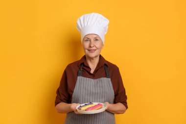 Turuncu arka planda eklerleri olan profesyonel bir şekerci.