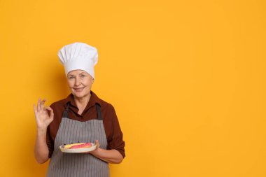 Turuncu arka planda iyi bir jest gösteren eklerli profesyonel şekerlemeci. Metin için boşluk