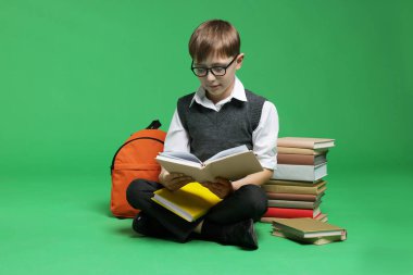 Sırt çantası ve yeşil arka plan kitapları olan tatlı bir okul çocuğu.