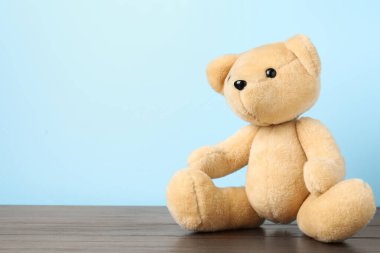 Ahşap masada açık mavi arka planda sevimli bir oyuncak ayı. Metin için boşluk