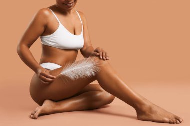 İç çamaşırlı kadın bej arka plandaki epilasyon işleminden sonra pürüzsüz cildini gösteriyor.