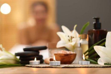 Güzel bir kadın masaj koltuğunda dinleniyor, farklı spa ürünlerine ve zambak çiçeklerine odaklanıyor.