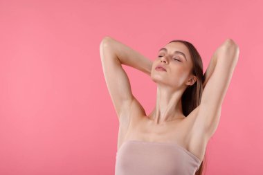 Pembe arkaplandaki epilasyondan sonra pürüzsüz cilt gösteren genç kadın, metin için boşluk