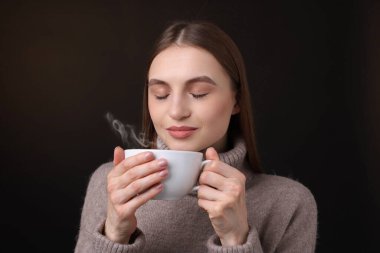 Kahverengi arka planda kahve fincanı olan bir kadın.