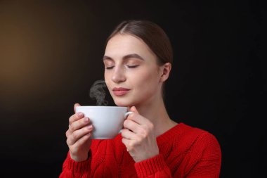 Kahverengi arka planda kahve fincanı olan bir kadın.